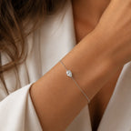 Bracelet LEANNA en or blanc 18 carats avec diamant poire de laboratoire porté au poignet d'une femme en blazer blanc