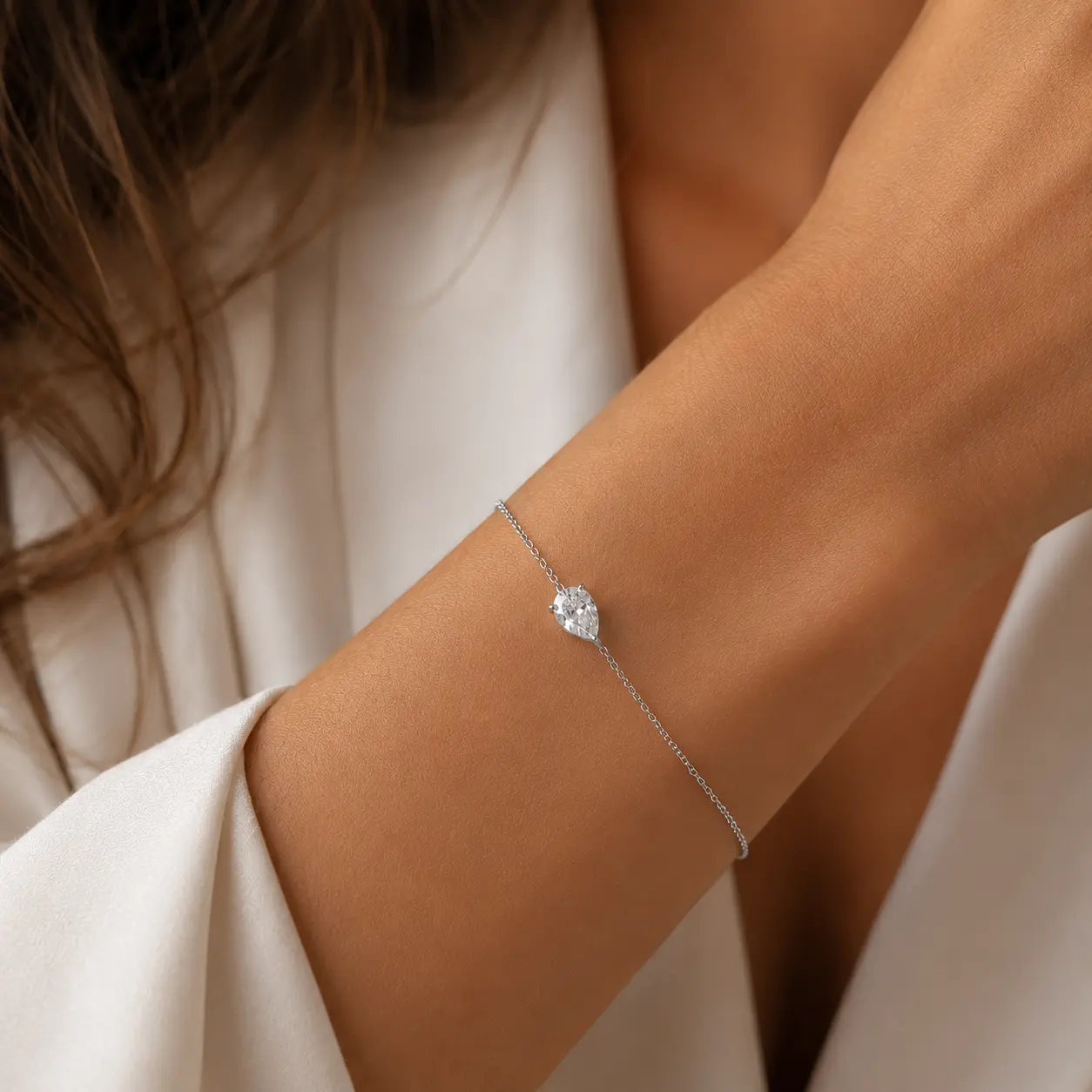 Bracelet LEANNA en or blanc 18 carats avec diamant poire de laboratoire porté au poignet d'une femme en blazer blanc