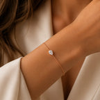vec diamant poire de laboratoire porté au poignet d'une femme en blazer blanc