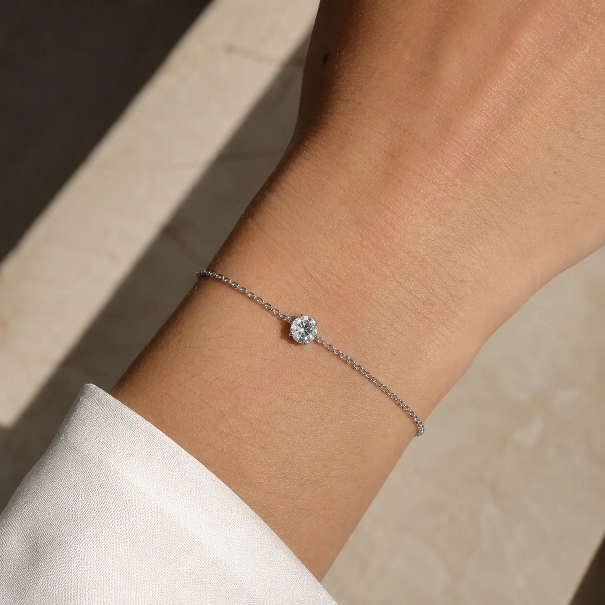 Bracelet SAONA en or blanc 18 carats avec diamant rond de laboratoire porté au poignet d'une femme en chemise blanche