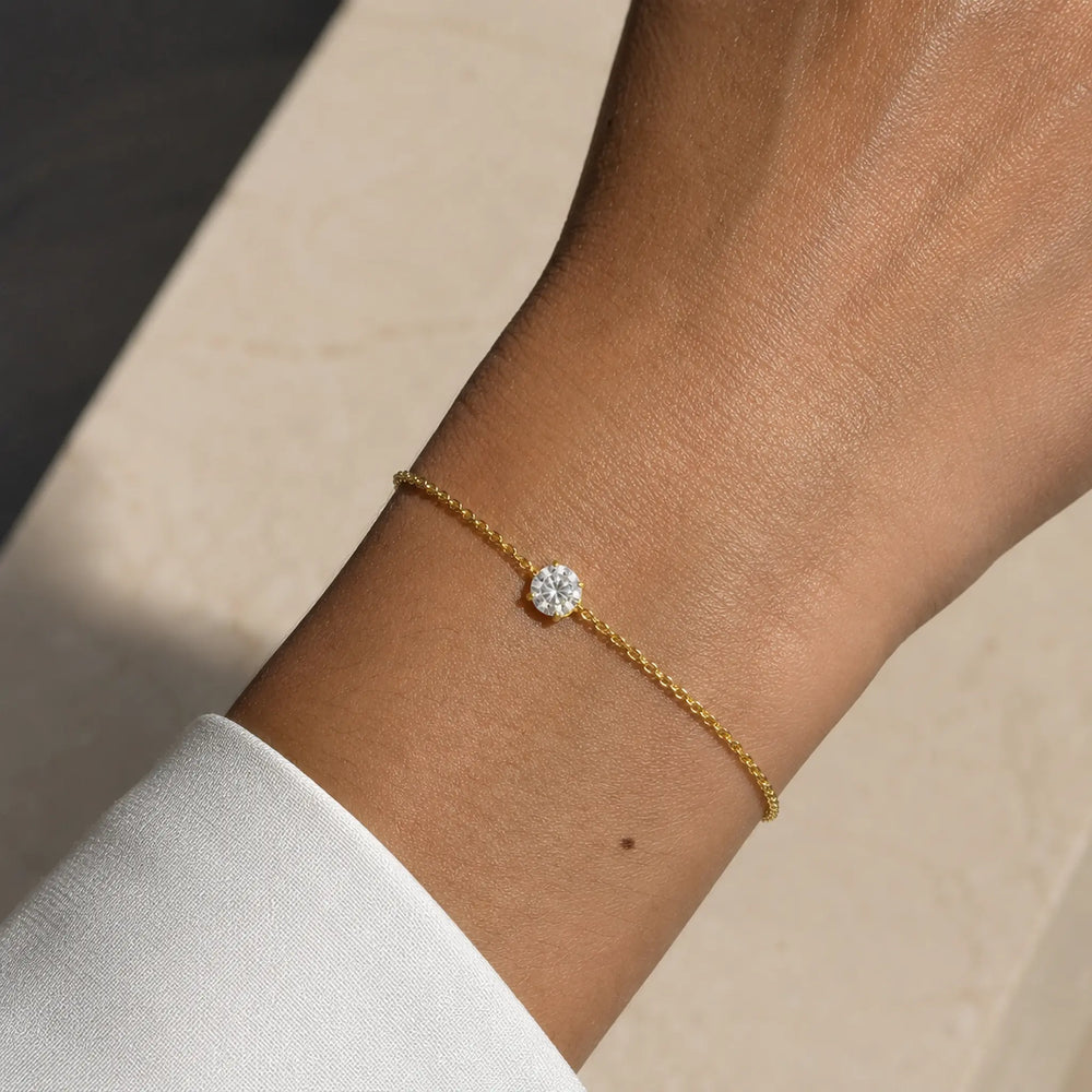 Bracelet SAONA en or jaune 18 carats avec diamant rond de laboratoire porté au poignet d'une femme en chemise blanche