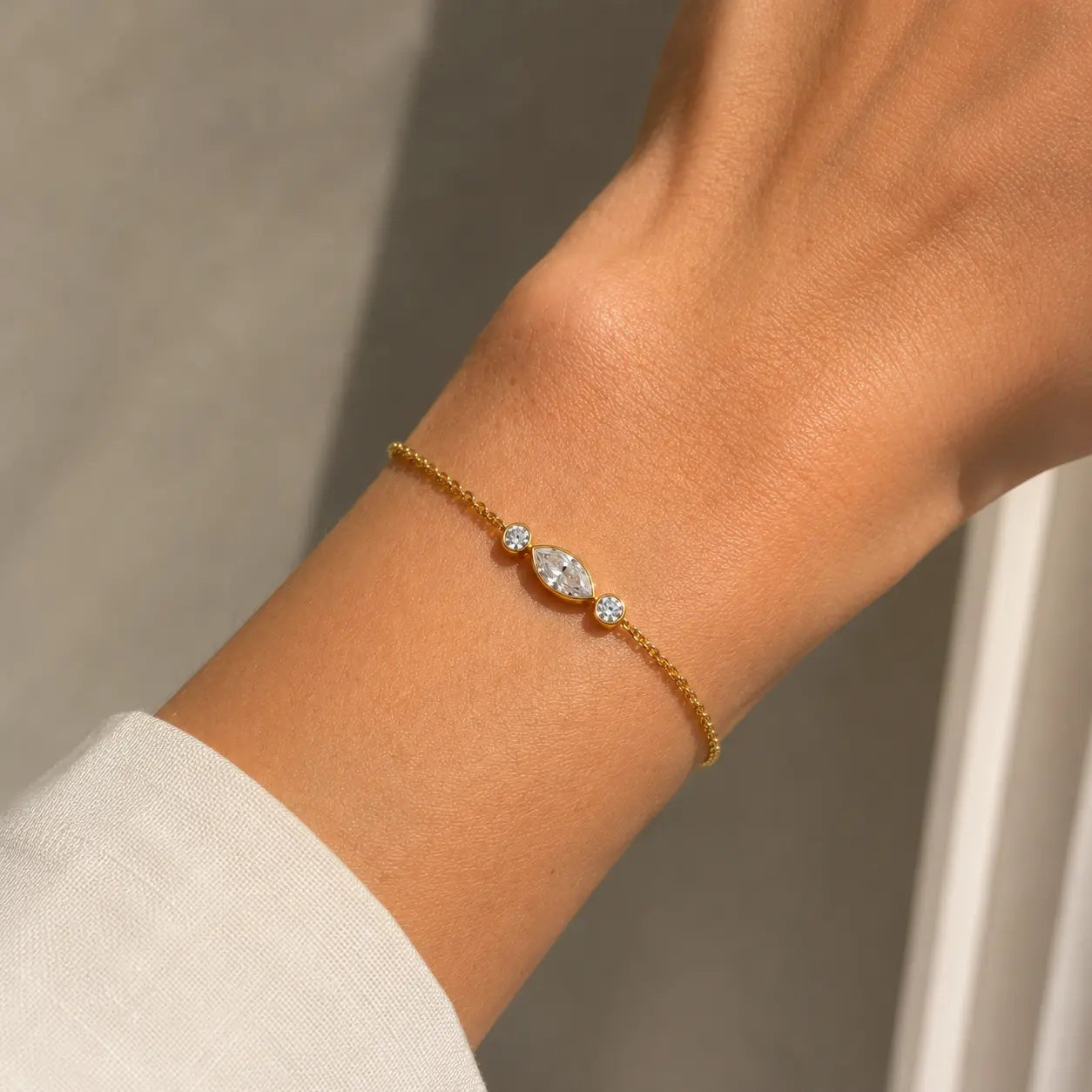 Bracelet Nina en or jaune 18 carats serti d’un diamant marquise et de deux diamants ronds, porté au poignet.